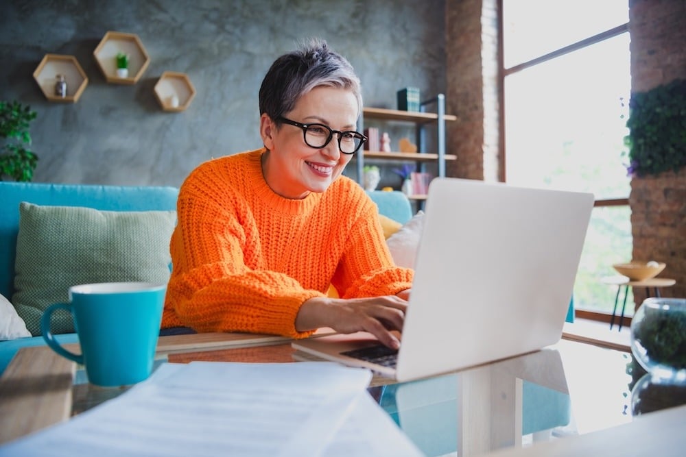 woman smiling while working at a desk on a laptop