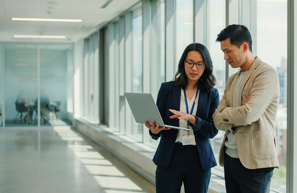 Two colleagues reviewing record status on a laptop